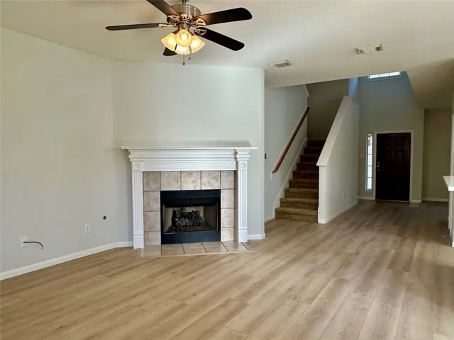 a view of an empty room with wooden floor fireplace and a window