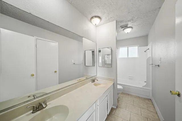 a spacious bathroom with a granite countertop sink a mirror and a bathtub