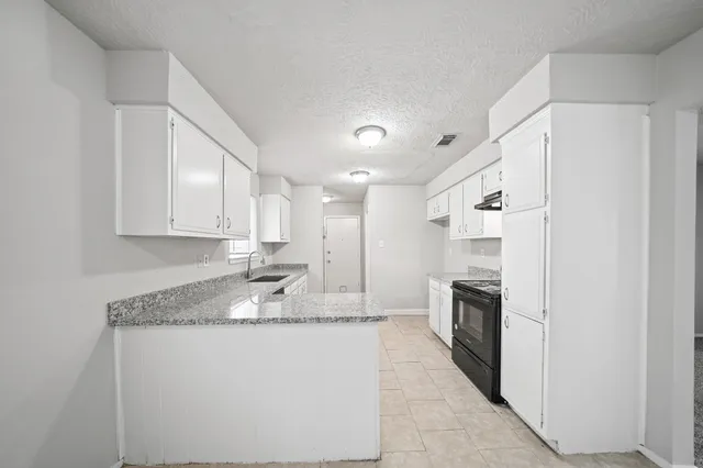 a kitchen with granite countertop a sink stove and refrigerator