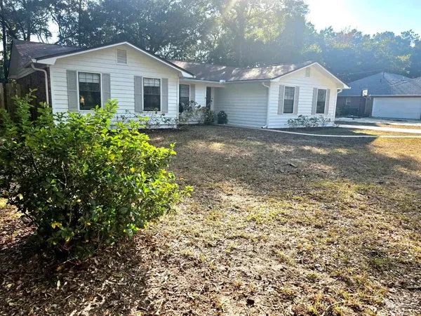 a view of a yard in front of a house with large trees