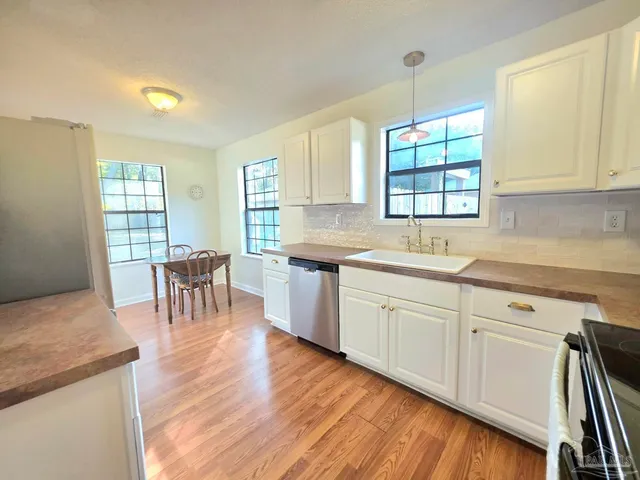 a kitchen with stainless steel appliances granite countertop a table chairs sink and cabinets