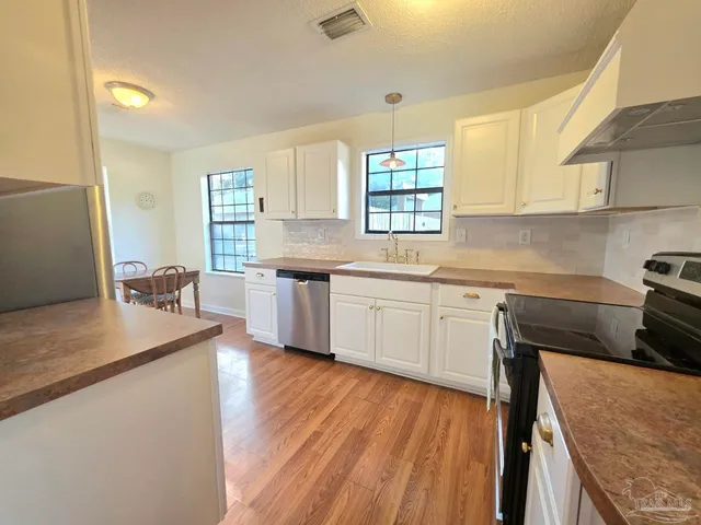 a kitchen with a sink a window stainless steel appliances and cabinets