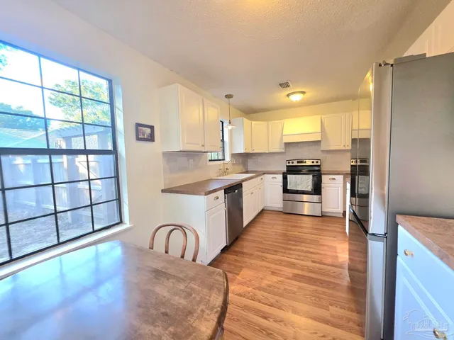 a large kitchen with granite countertop a stove a sink a refrigerator dining table and chairs