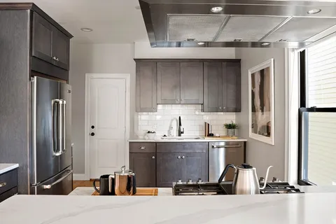 a room with stainless steel appliances kitchen island granite countertop a refrigerator and a sink