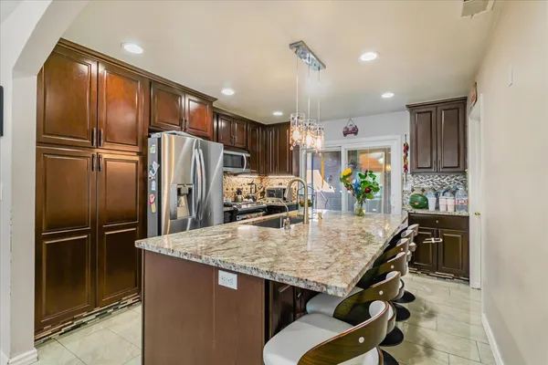 a kitchen with granite countertop a refrigerator and microwave