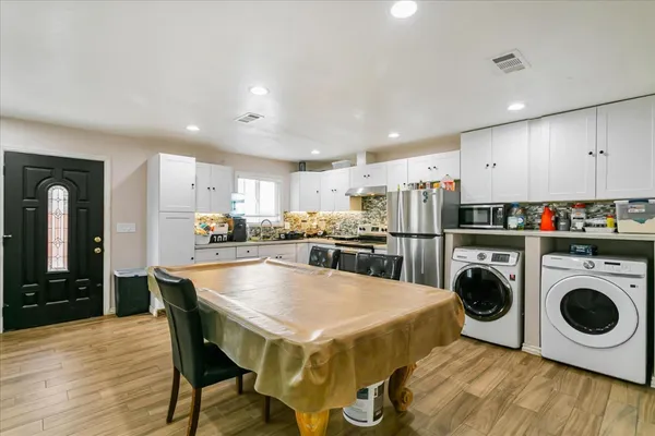 a kitchen with a dining table chairs refrigerator and cabinets