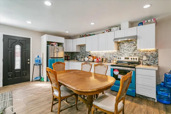 a kitchen with granite countertop a dining table chairs cabinets and stainless steel appliances