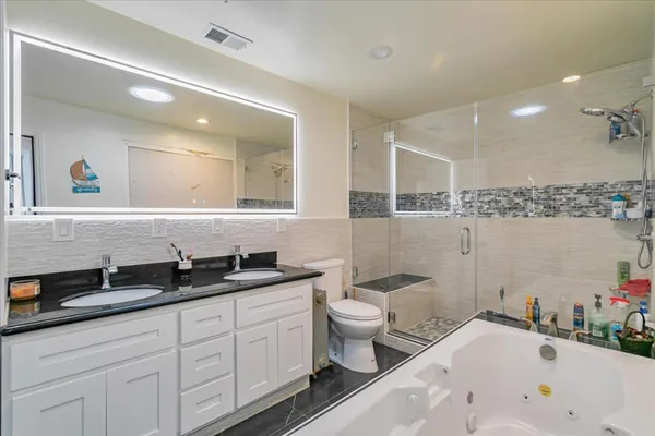 a spacious bathroom with a bathtub sink mirror and toilet