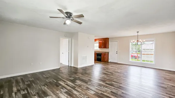 a view of an empty room with a window and wooden floor