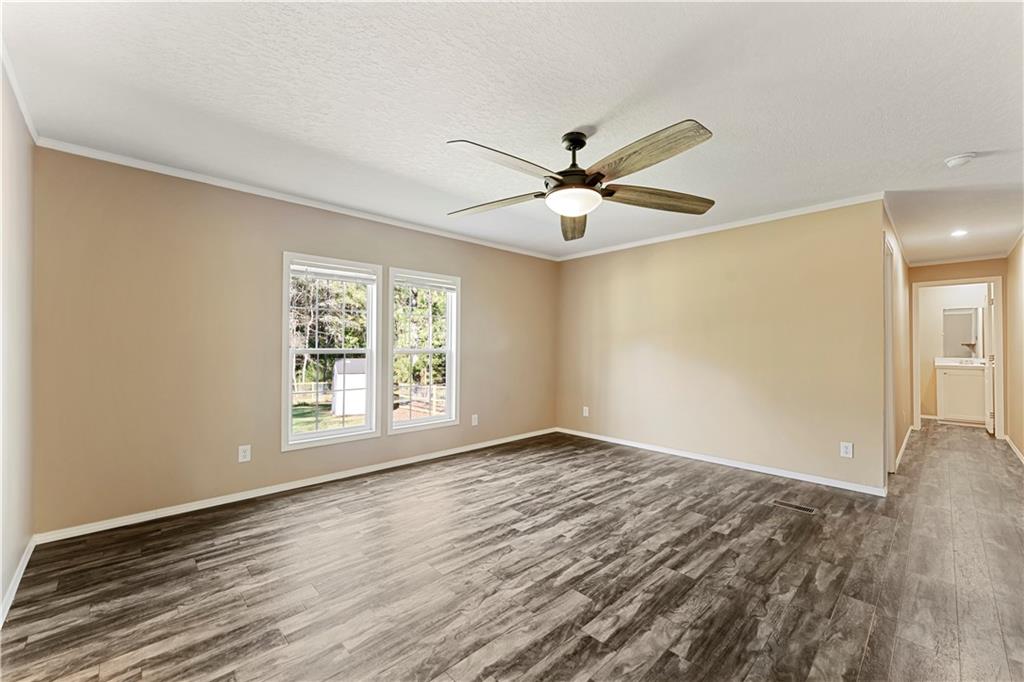 89 Ridge Road Seale, AL 36875 - Photo 39 of 46 Expansive room featuring wood-finish flooring, two large windows, a ceiling fan with integrated lighting, and neutral wall tones