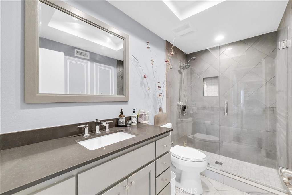 1417 West James Way Anaheim, CA 92801 - Photo 24 of 40 a bathroom with a granite countertop sink a toilet a mirror and shower