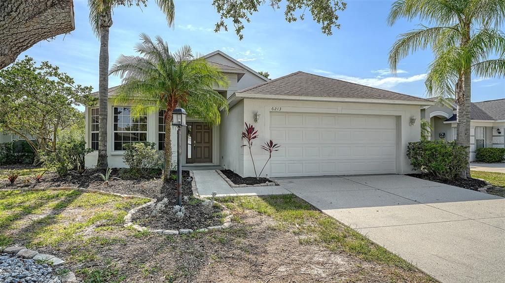 a view of a house with small yard plants and palm trees
