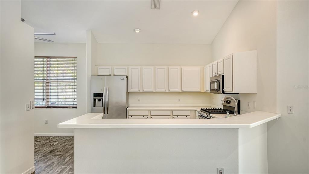 6213 Willet Court Lakewood Ranch, FL 34202 - Photo 12 of 74 a kitchen with stainless steel appliances granite countertop a sink a stove a refrigerator a counter top space and cabinets