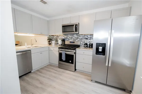a kitchen with white cabinets stainless steel appliances and a sink
