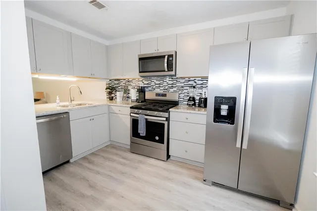 a kitchen with white cabinets stainless steel appliances and a sink