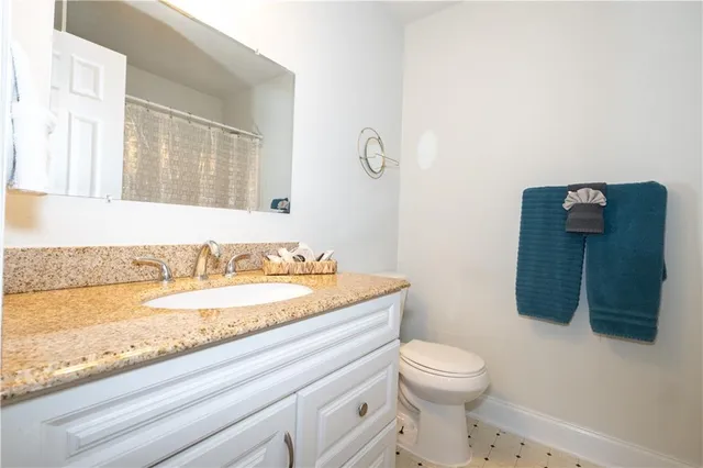 a bathroom with a granite countertop sink a toilet and a mirror