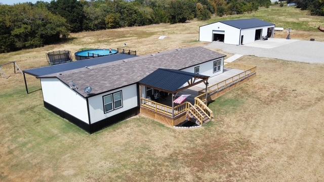 36469 1330th Road Wewoka, OK 74884 - Photo 1 of 39 White siding with black trim, a covered porch, an expansive wood deck, a separate metal building, and a paved outdoor area