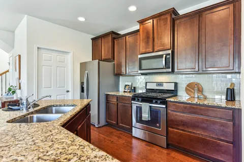 a kitchen with granite countertop a stove a sink and a microwave
