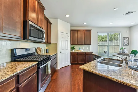a kitchen with granite countertop kitchen island stainless steel appliances a stove sink and cabinets