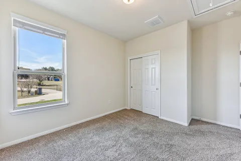 a view of an empty room with window and wooden floor