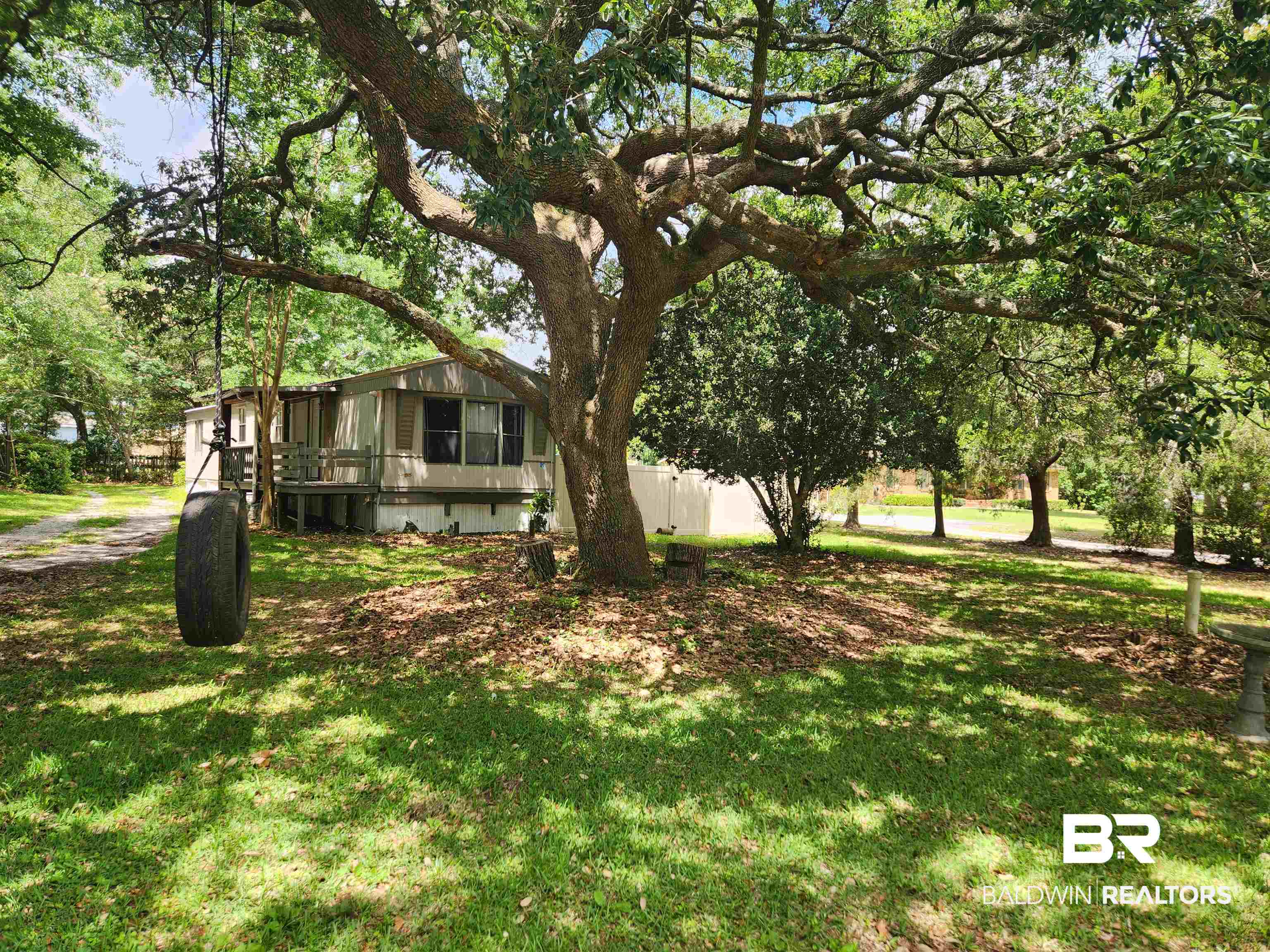 23051 Fritz Lane Foley, AL 36535 - Photo 2 of 26 Spacious front yard featuring a mature oak tree, a gravel driveway, and a partially covered porch