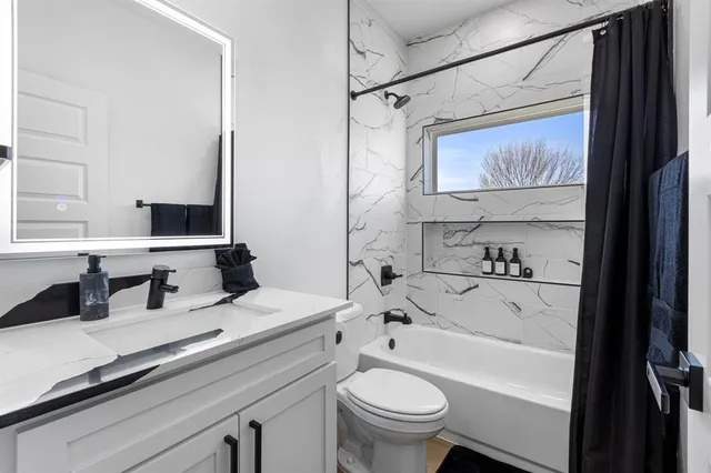 a bathroom with a bathtub sink mirror and toilet
