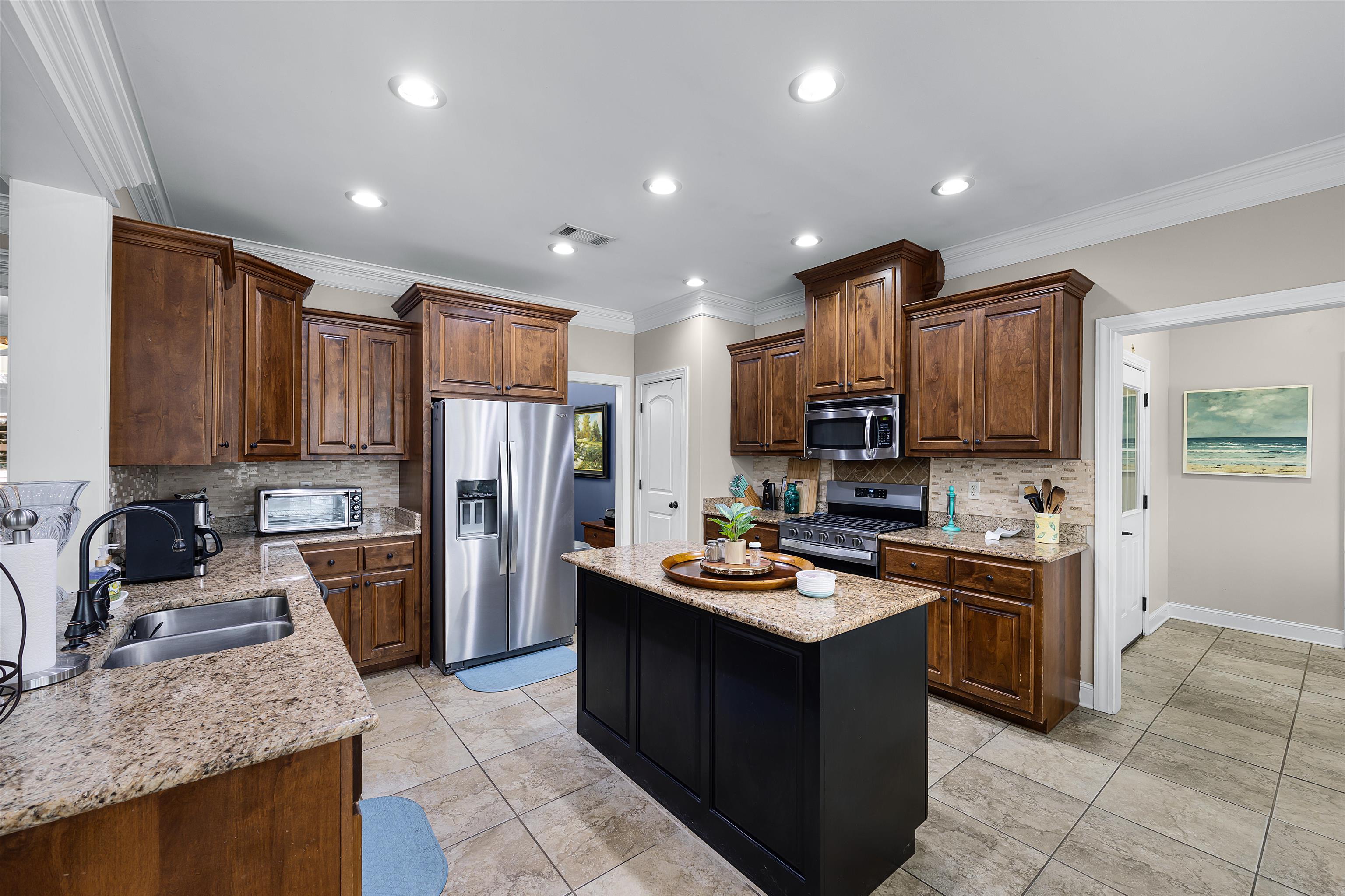 3285 Shadowood Lane Corinth, MS 38834 - Photo 12 of 30 Kitchen with stainless steel appliances, light stone counters, crown molding, a center island, and recessed lighting