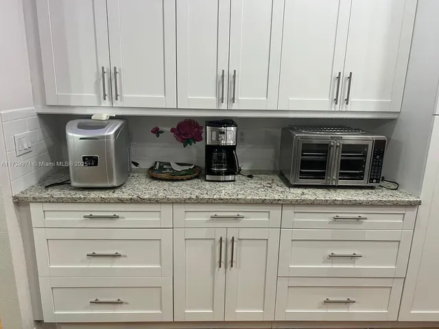 a kitchen with granite countertop white cabinets and a stove