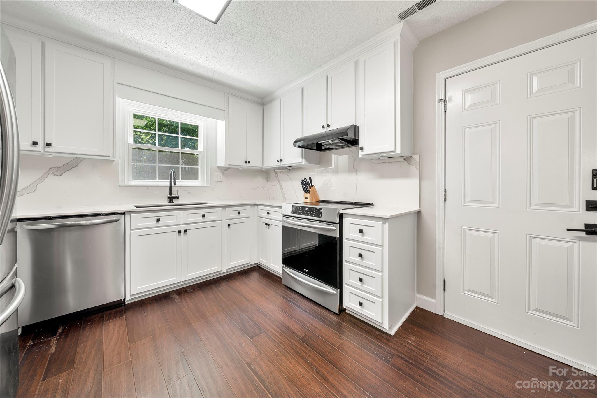 6433 Round Hill Road Charlotte, NC 28211 - Photo 16 of 33 a kitchen with stainless steel appliances white cabinets and a wooden floors