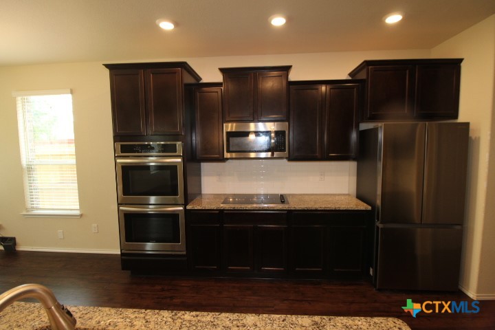 1202 Stonewall Ridge Harker Heights, TX 76548 - Photo 2 of 14 a kitchen with stainless steel appliances wooden cabinets and granite counter tops