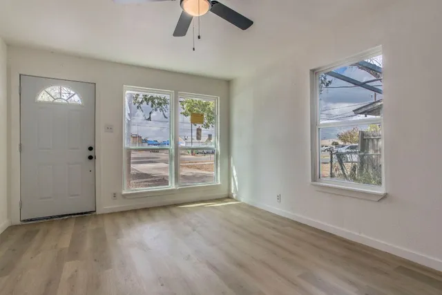 a view of an empty room with a window and wooden floor