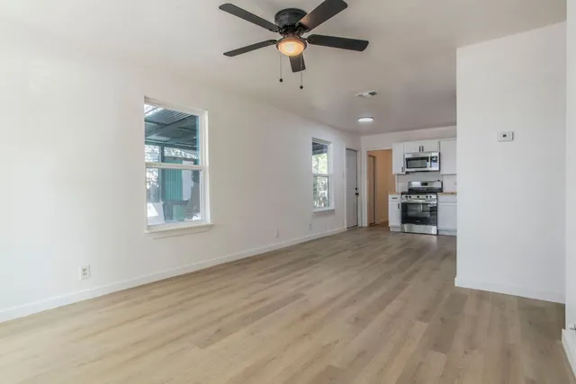 a view of empty room with wooden floor and fan