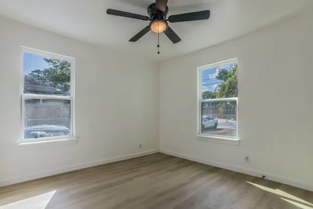 an empty room with a window and a fan