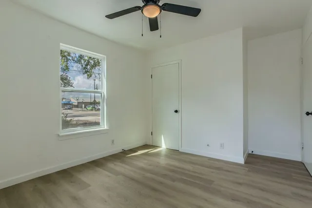 a view of an empty room with window and wooden floor