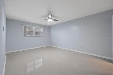 an empty room with a window and ceiling fan