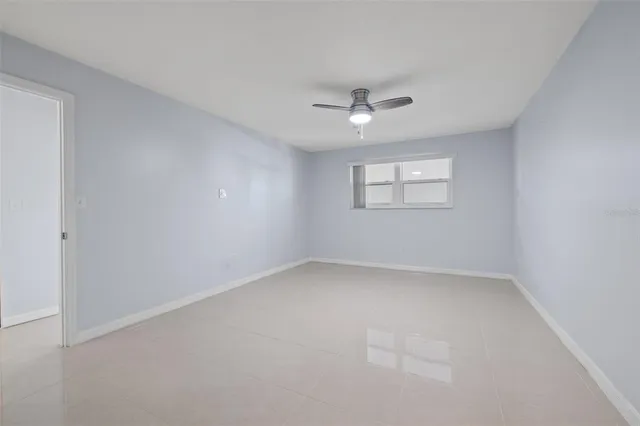 an empty room with a window and ceiling fan