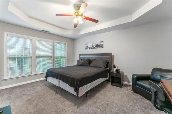 a spacious bedroom with a bed a chair and a large window