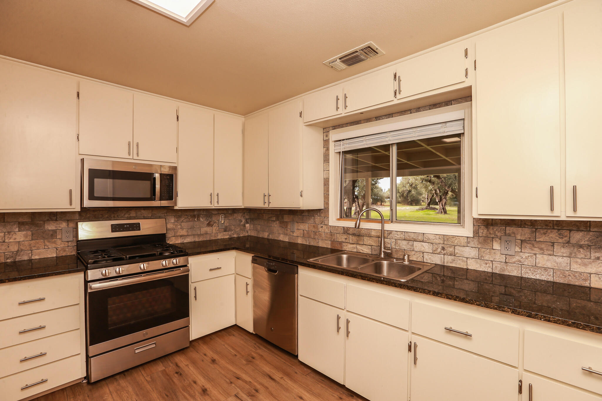 5572 Olive Street Anderson, CA 96007 - Photo 9 of 31 a kitchen with granite countertop a sink cabinets stainless steel appliances and a counter space