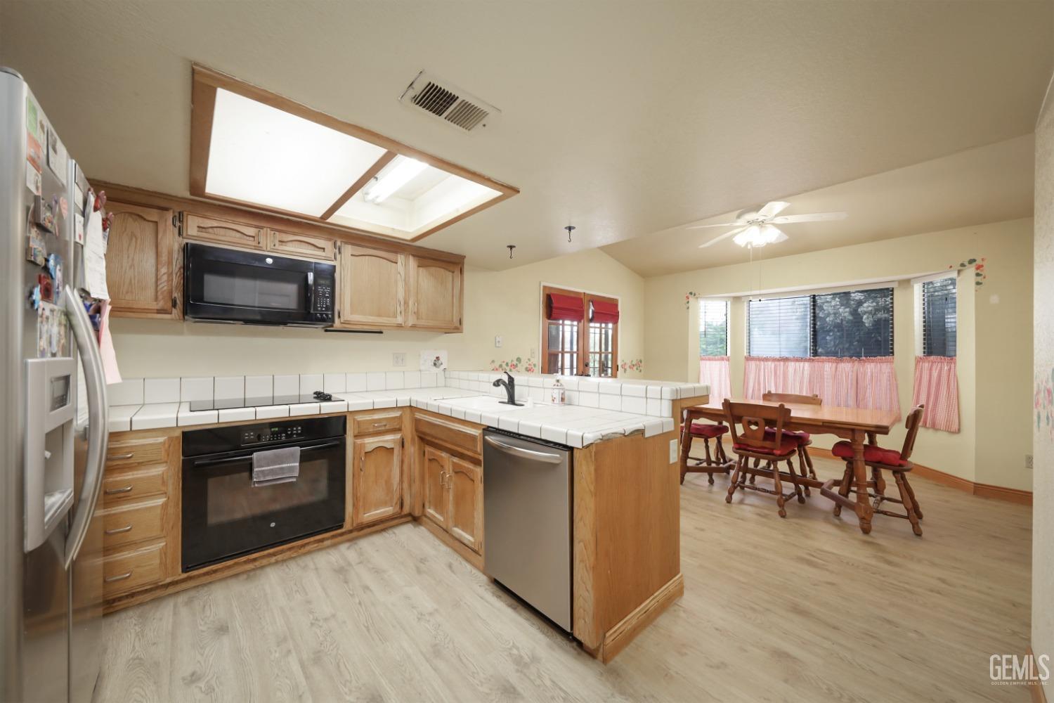 Undisclosed Address Bakersfield, CA 93314 - Photo 11 of 29 a kitchen with stainless steel appliances granite countertop a stove top oven a sink dishwasher a dining table and chairs with wooden floor