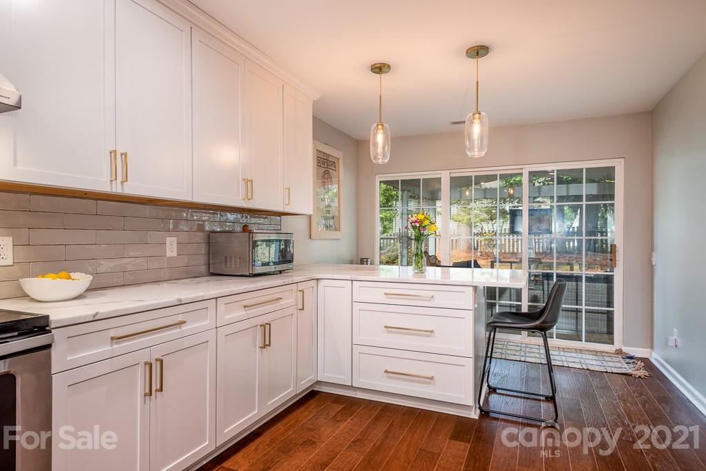 18122 Bluff Inlet Road Cornelius, NC 28031 - Photo 13 of 34 a kitchen with stainless steel appliances granite countertop a stove a sink and white cabinets with wooden floors