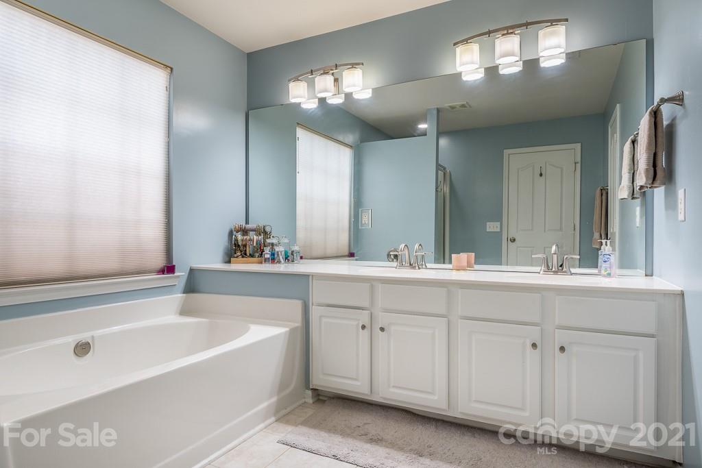 18122 Bluff Inlet Road Cornelius, NC 28031 - Photo 22 of 34 a bathroom with a bathtub a double vanity sink and mirror