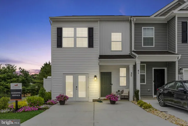 a front view of a house with a yard and potted plants