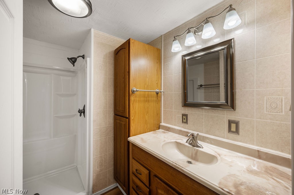 58 Rock Ridge Road Mineral Wells, WV 26150 - Photo 14 of 38 Bathroom featuring a single-basin vanity with an integrated countertop, wood-finish cabinetry, and a framed mirror