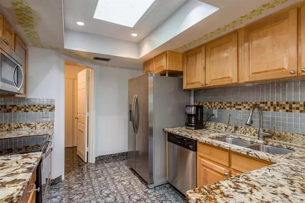 a kitchen with stainless steel appliances granite countertop a refrigerator a stove and a sink