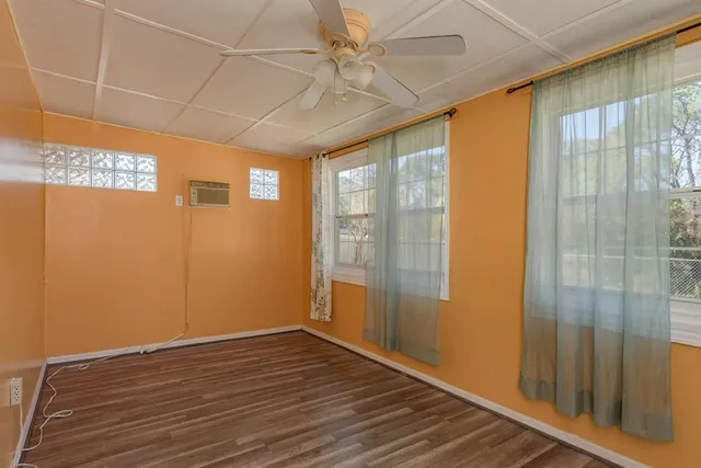 a view of an empty room with wooden floor and a window