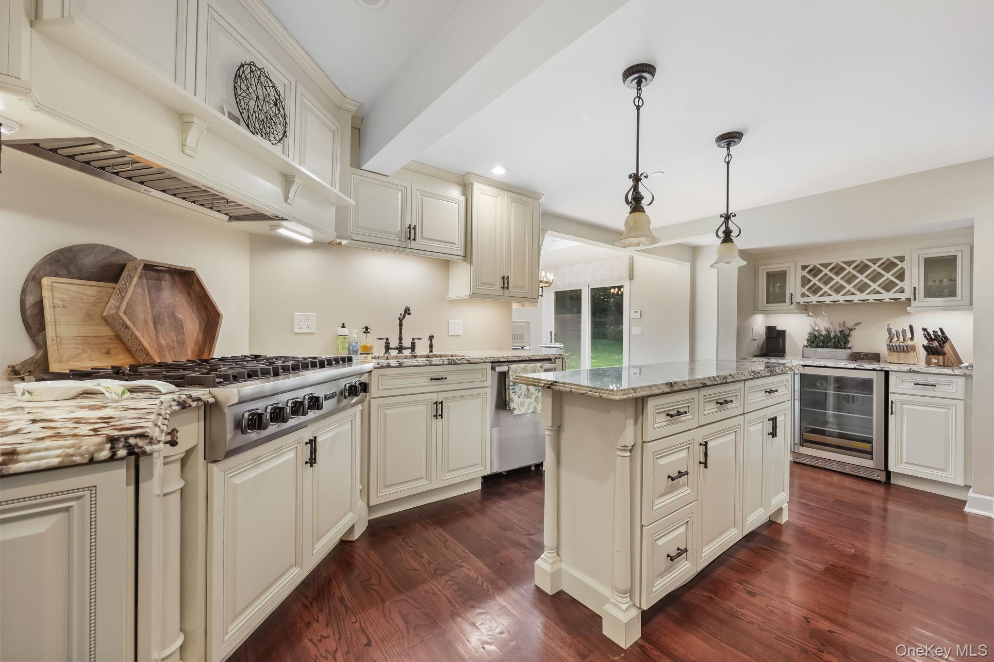 777 Armonk Road Mount Kisco, NY 10549 - Photo 9 of 44 Kitchen with decorative light fixtures, light stone countertops, dark wood finished floors, premium range hood, and wine cooler