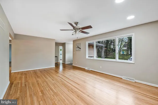 a view of an empty room with wooden floor and a window