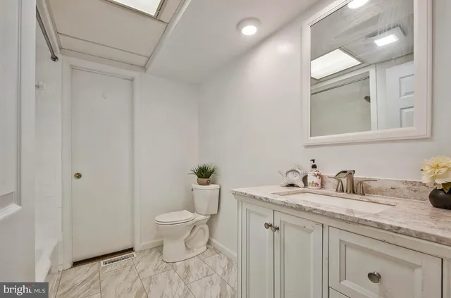 a bathroom with a granite countertop sink a toilet and a mirror