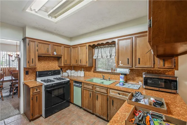 a kitchen that has a sink a stove and a wooden cabinets