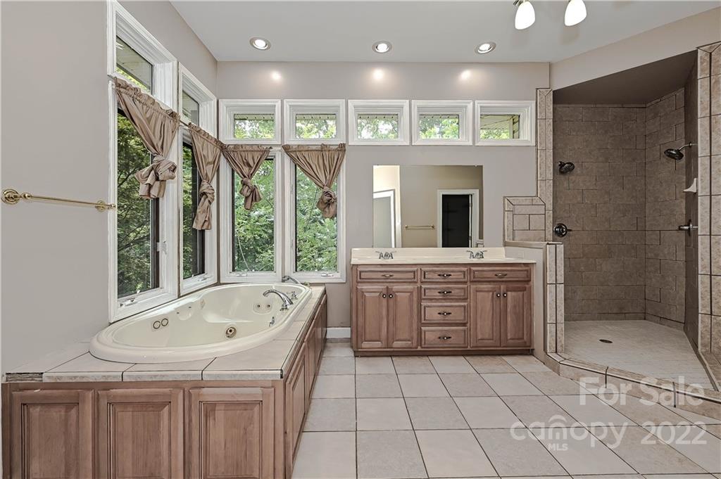 6430 Waters Edge Drive Midland, NC 28107 - Photo 23 of 48 a bathroom with a tub a sink and a large mirror